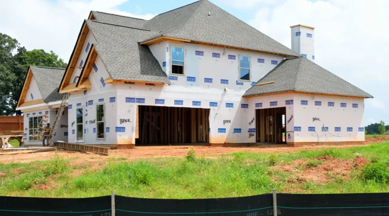 New home construction site with wooden framing and building materials under a clear sky